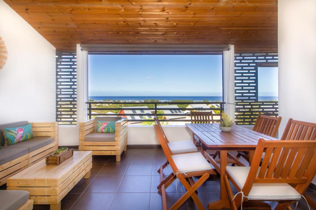 a room with a table and chairs and a large window at Ormeau - bel apt avec magnifique vue mer à la Saline les bains in La Saline les Bains