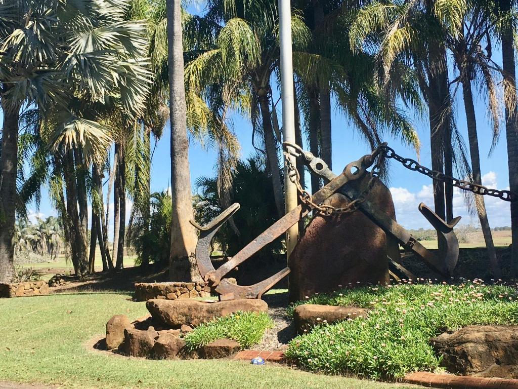 a statue of a anchor with a chain and palm trees at Villa 21 The Coral Cove Resort in Elliott Heads