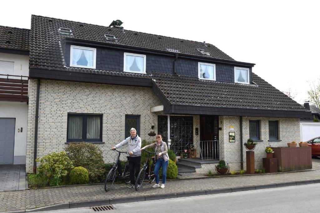 due persone in piedi di fronte a una casa con le loro biciclette di Haus Wegener a Bad Sassendorf