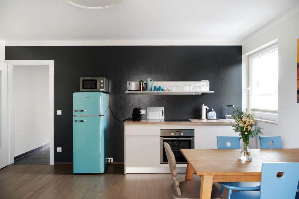 a kitchen with a blue refrigerator and a table at HOMEBOUND APARTMENTS Salzburg City II - contactless check-in in Salzburg