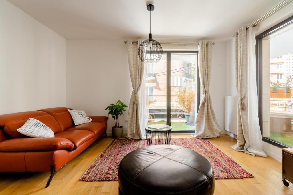 a living room with a leather couch and a large window at 3 p 60 M2 Lesapparts Paris-Clichy terrasse équipée et wifi gratuit in Clichy