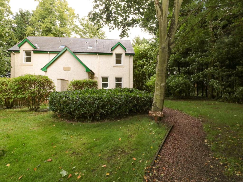 una casa blanca con un árbol en el patio en Gardener's Cottage, en Allanton