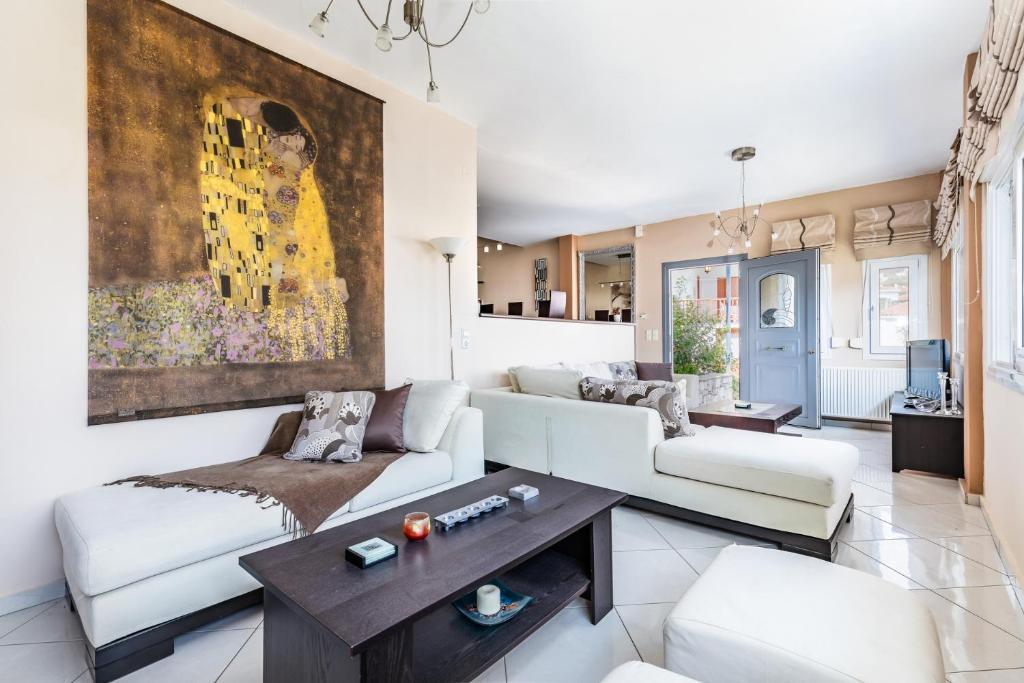 a living room with white furniture and a painting on the wall at Althea Apartment in Skopelos Town
