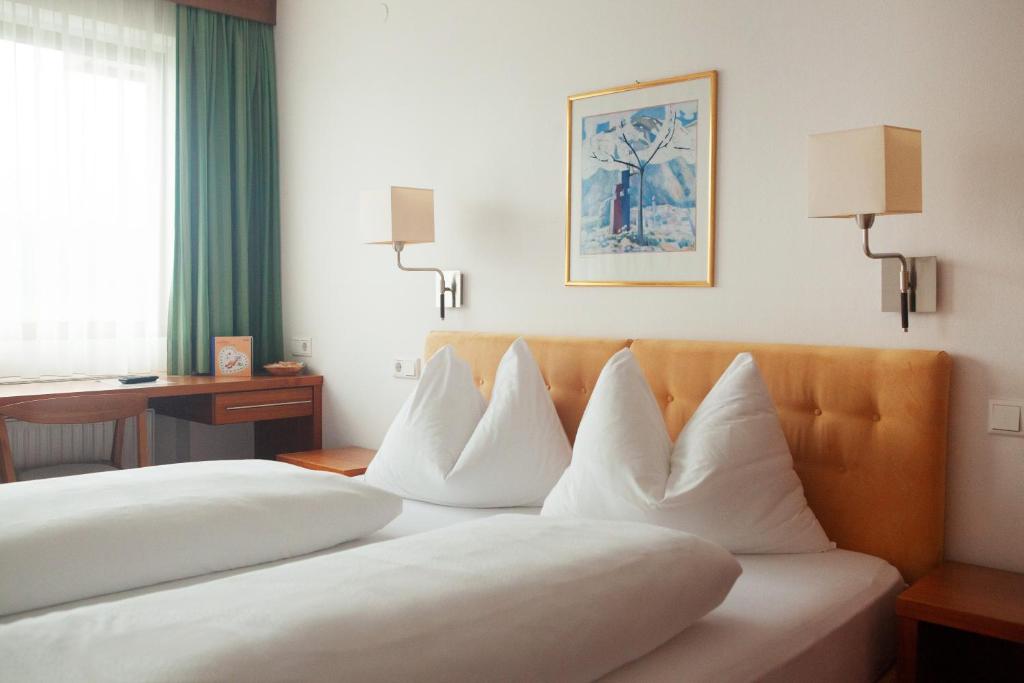 una camera d'albergo con due letti con cuscini bianchi di Sportpension Thayer a Piesendorf
