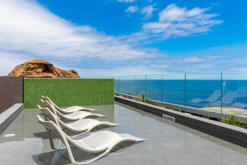 a row of white chairs sitting on top of a building at Aqua Natura Bay in Porto Moniz