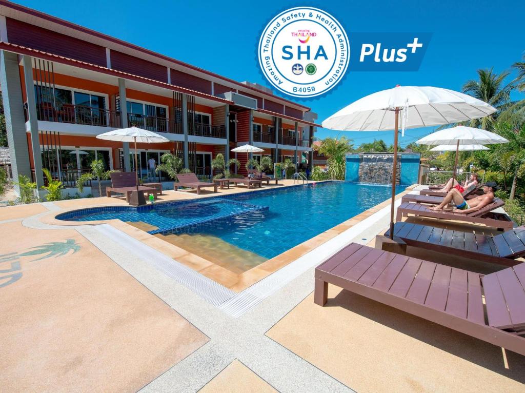 a pool at a hotel with two people sitting on benches at Hatzanda Lanta Resort - SHA Extra Plus in Ko Lanta