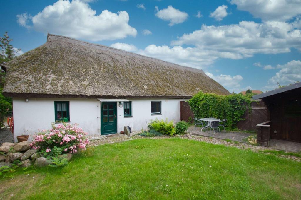 a cottage with a thatched roof with a yard at wassernahes Haus mit Terrasse und Garten - Ferienhaus Storchennest Haus rechte Seite in Wiek auf Rügen 