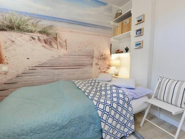 ein Schlafzimmer mit einem Bett und einem Wandbild vom Strand in der Unterkunft Traper Apartamenty in Sopot