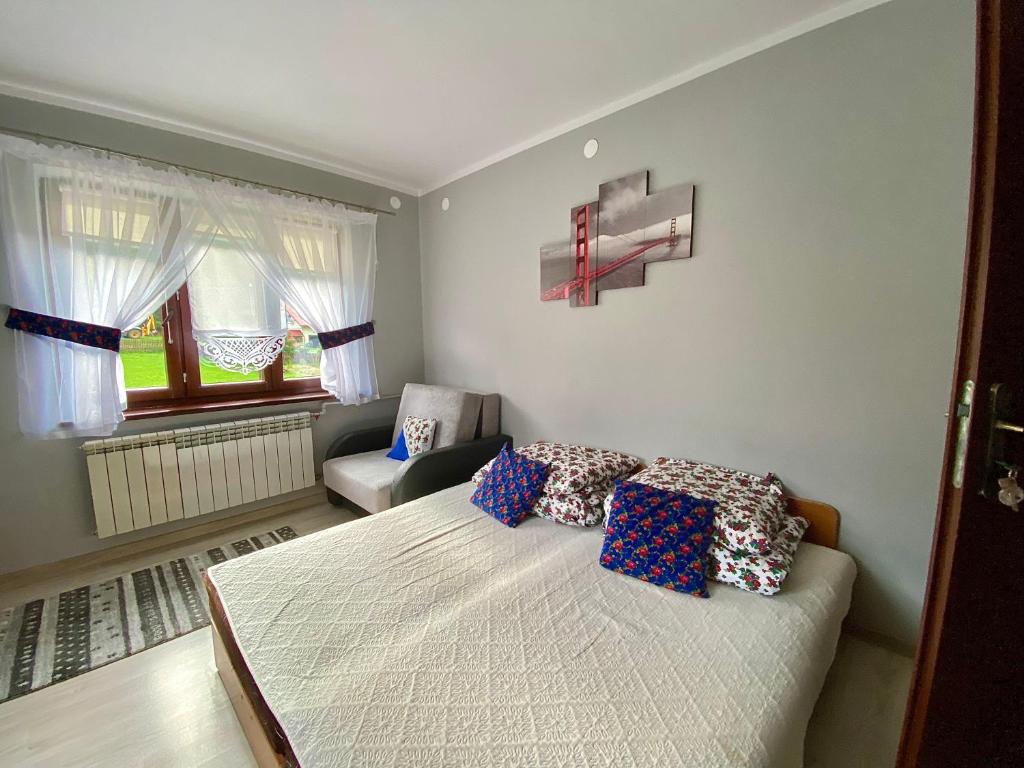 een slaapkamer met een bed, een stoel en een raam bij Noclegi u Marii - Koninki in Poręba Wielka