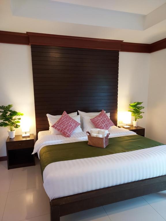 1 dormitorio con 1 cama grande con almohadas rosas y blancas en Aromdee at Naithon Beach, en Nai Thon Beach