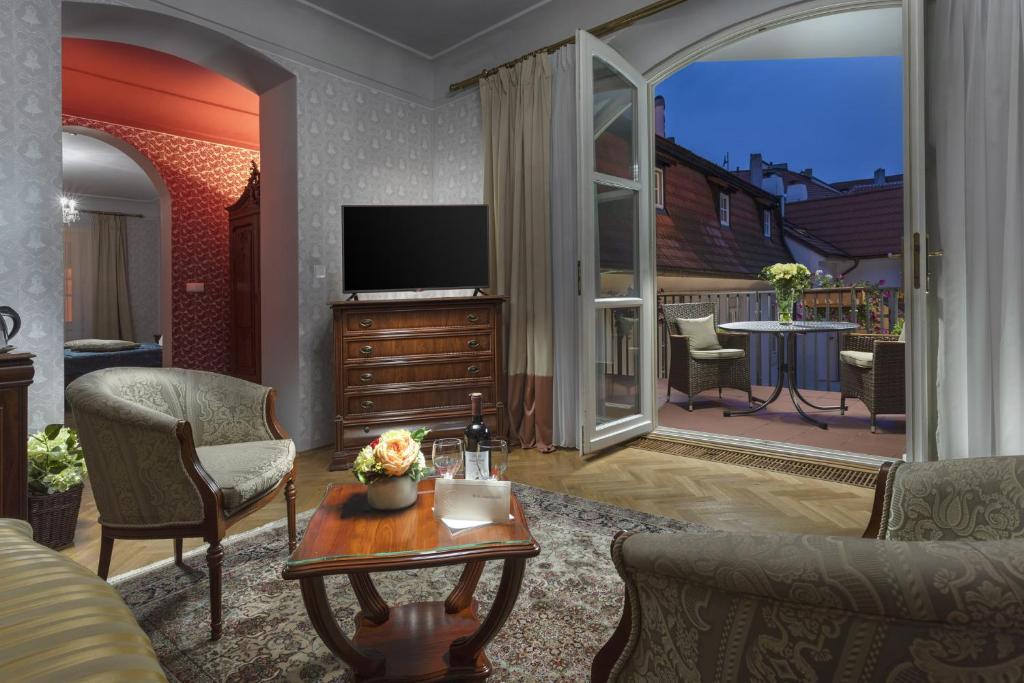 a living room with a television and a balcony at Boutique Hotel Constans in Prague