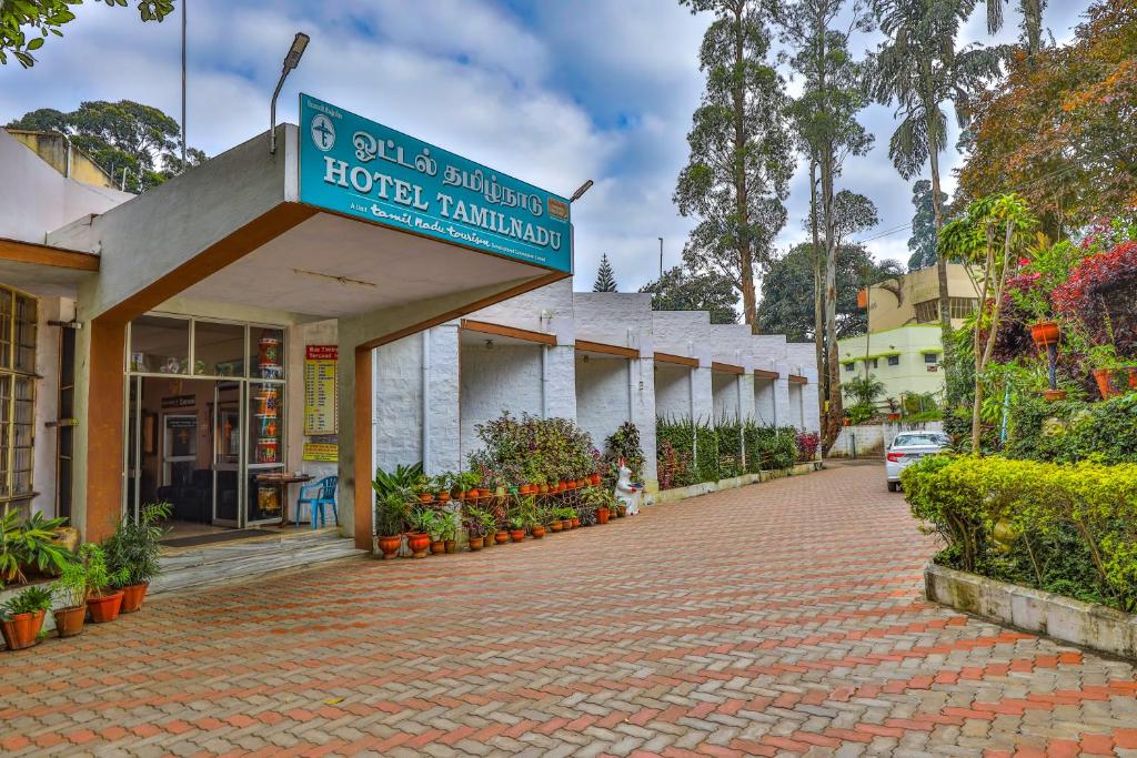 a hotel building with a sign on a brick road at Hotel TamilNadu - Yercaud in Yercaud