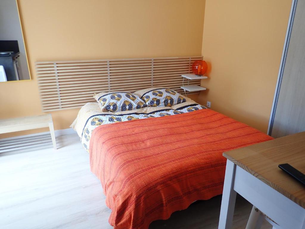 a bedroom with a large bed with a red blanket at Proche GR34 , Studio "Estrella" , petit cocon accueillant in Hillion