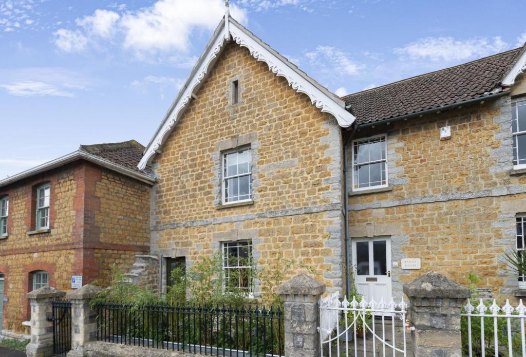 an old brick house with a white fence at Round House Cottage in Castle Cary