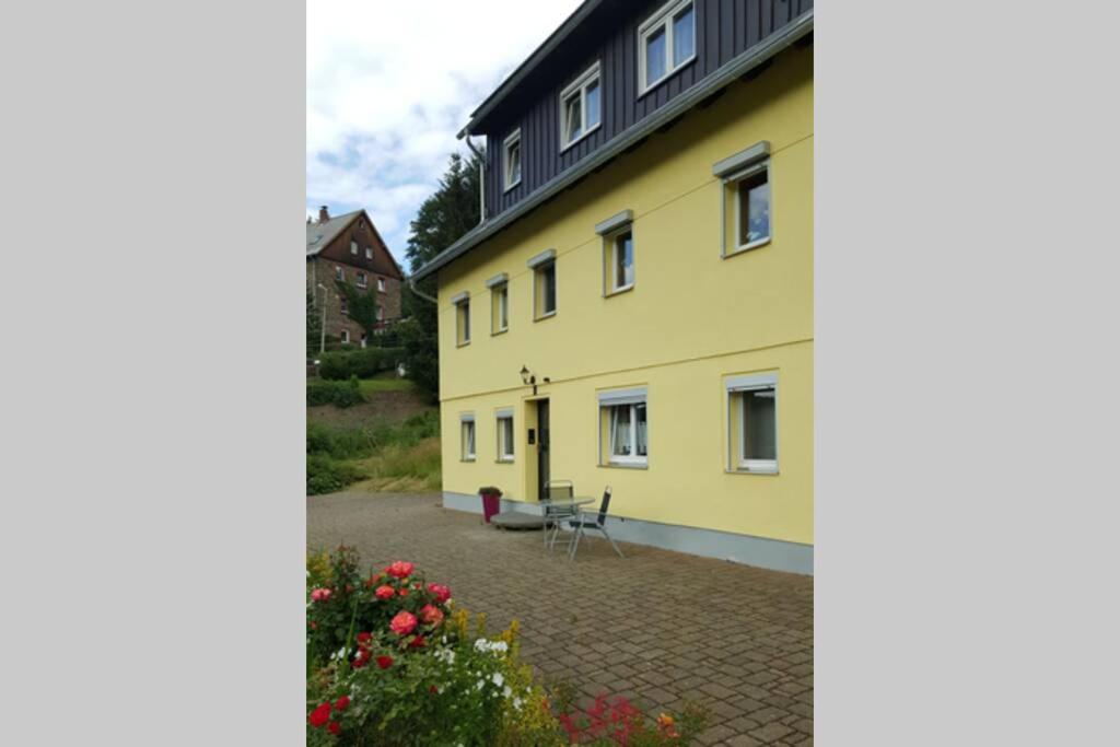 ein gelbes Gebäude mit einer Bank im Innenhof in der Unterkunft Sonnenblick Rittersgrün II in Breitenbrunn