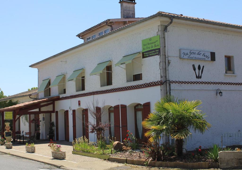 a white building with a sign on the side of it at Au Feu de Bois in Amou