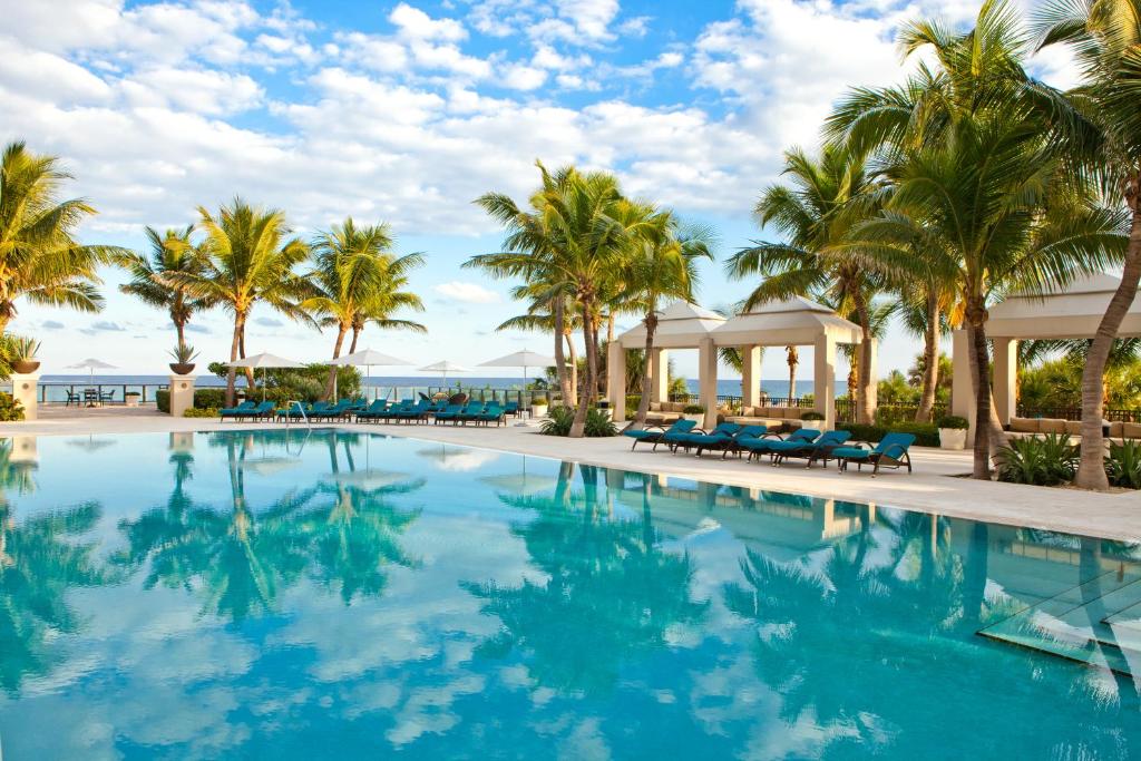 a pool at the resort with palm trees at Ritz Carlton Luxurious Residence on Singer Island in Riviera Beach