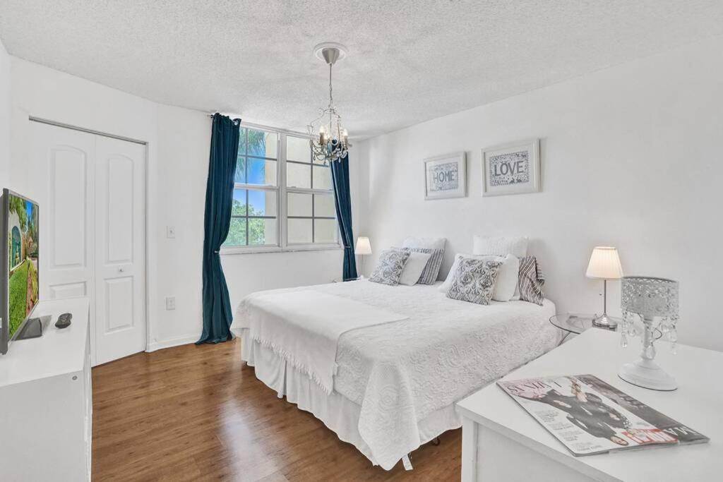a white bedroom with a bed and a window at Renovated cozy The yacht club at aventura Parking included in Miami