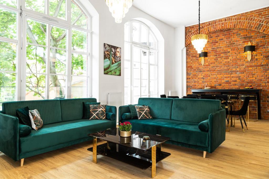 a living room with two green couches and a piano at Prestige Apartments 12 in Wrocław
