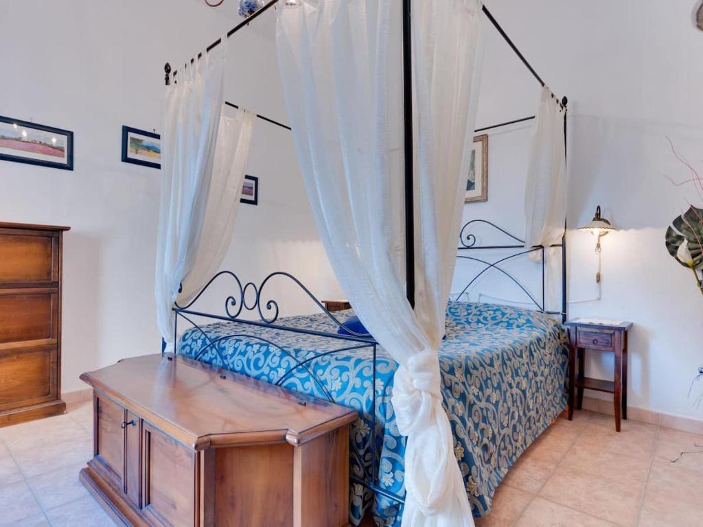 モンテカティーニ・ヴァル・ディ・チェーチナにあるDimora tipica toscanaのベッドルーム(天蓋付きベッド1台、木製テーブル付)