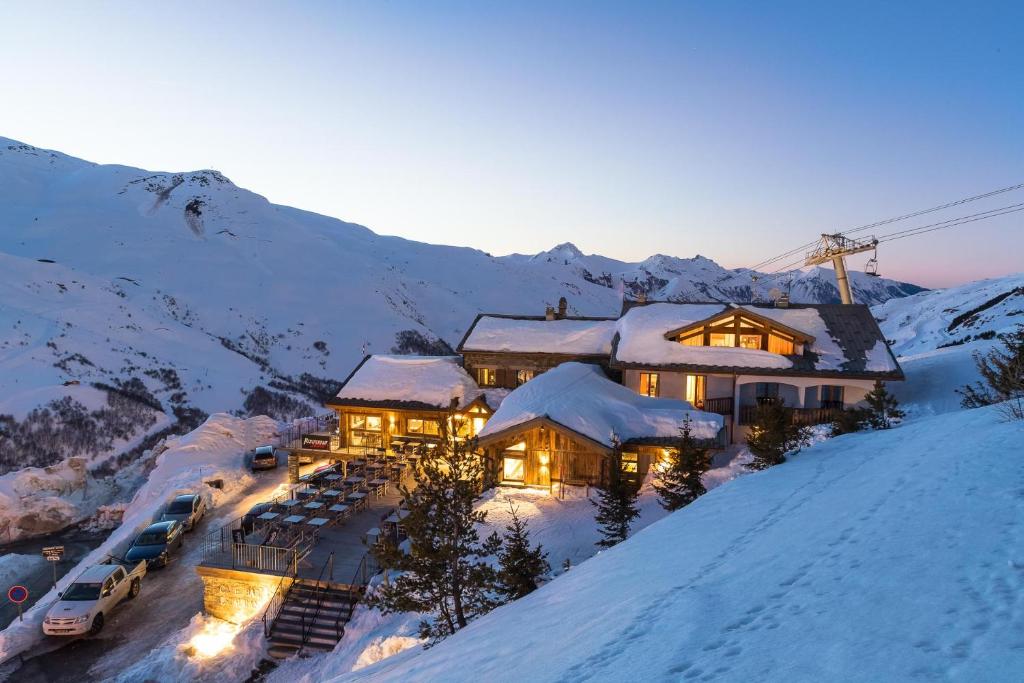 a house in the snow with cars parked in front at Hillary Hotel in Les Menuires