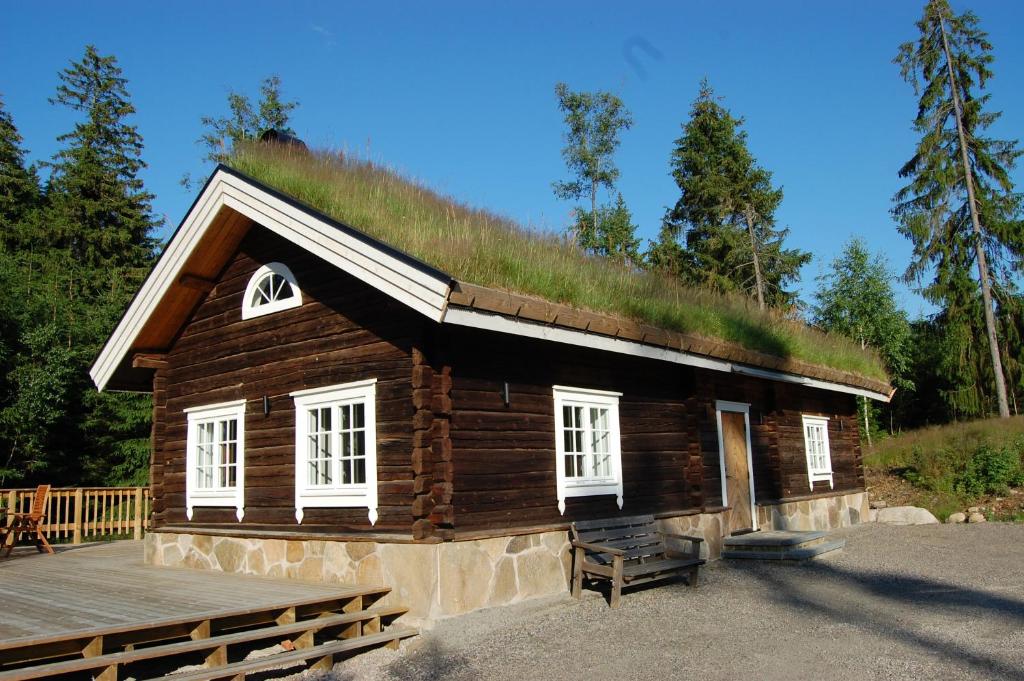 uma cabana de madeira com telhado de relva em Latitude em Torestorp