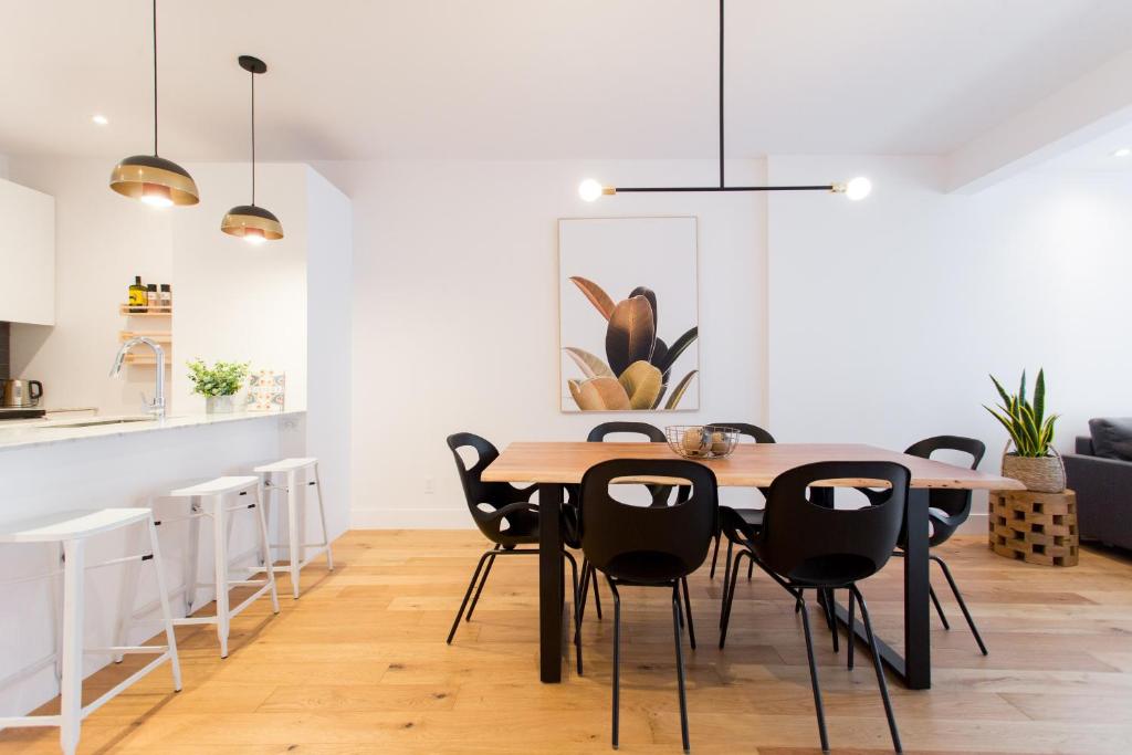 a dining room with a wooden table and black chairs at Hip, Stylish Apartment in Little Italy by Den Stays A in Montréal