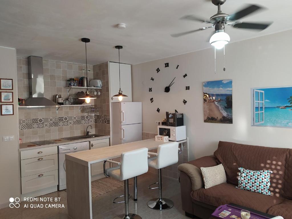 een keuken met een tafel en een bank en een klok aan de muur bij Muy cerca de la playa Gran piscina wifi gratis Port Aventura in Miami Platja