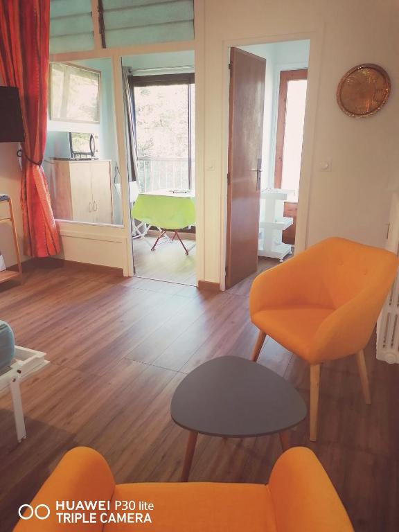 a living room with an orange chair and a table at Superbe studio avec ascenseur à 50 mètres des cures et du centre ville in Vernet-les-Bains