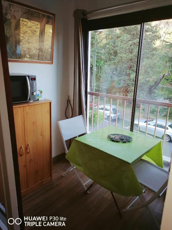 a green table and chairs in a room with a window at Superbe studio avec ascenseur à 50 mètres des cures et du centre ville in Vernet-les-Bains