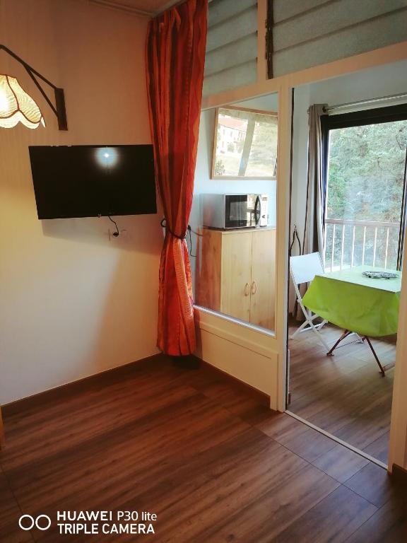 a living room with a television and a table and a window at Superbe studio avec ascenseur à 50 mètres des cures et du centre ville in Vernet-les-Bains