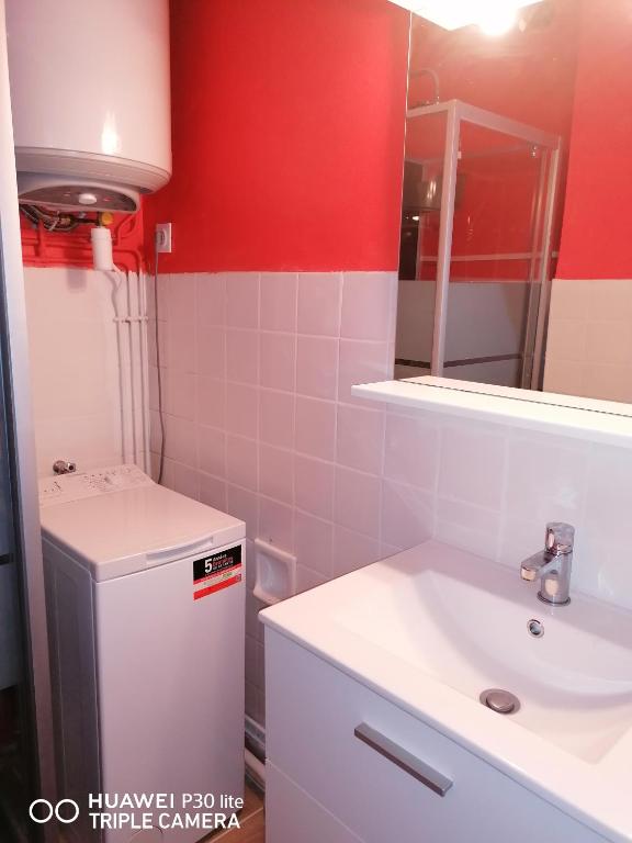 a bathroom with a white sink and a red wall at Superbe studio avec ascenseur à 50 mètres des cures et du centre ville in Vernet-les-Bains