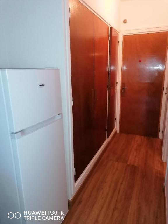 a kitchen with a white refrigerator and a wooden floor at Superbe studio avec ascenseur à 50 mètres des cures et du centre ville in Vernet-les-Bains