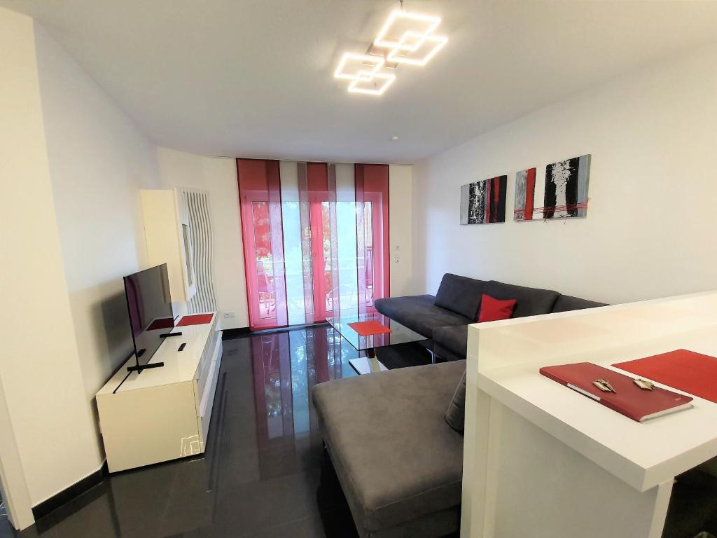 a living room with a couch and a desk with a television at Ihr Ticket ins Grüne - Topmoderne 5-Sterne-Ferienwohnung in Bad Kreuznach