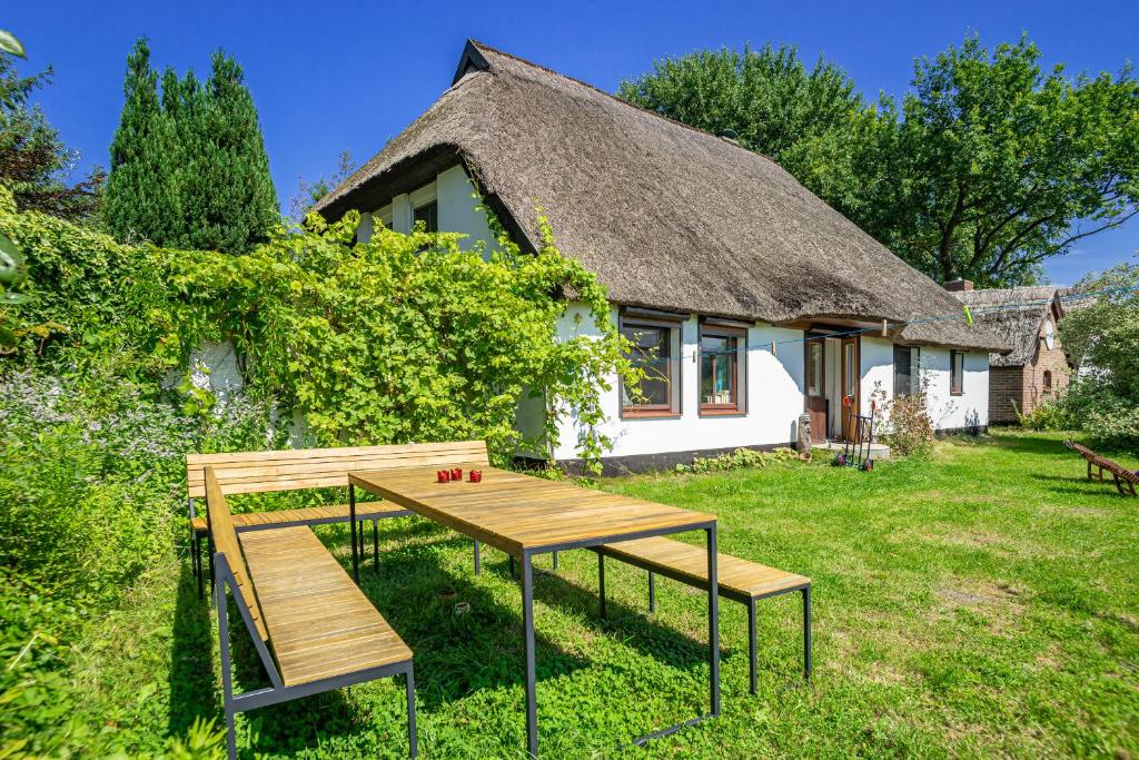 a table and benches in front of a thatched house at Fischerhus Ummanz FW2 in Ummanz