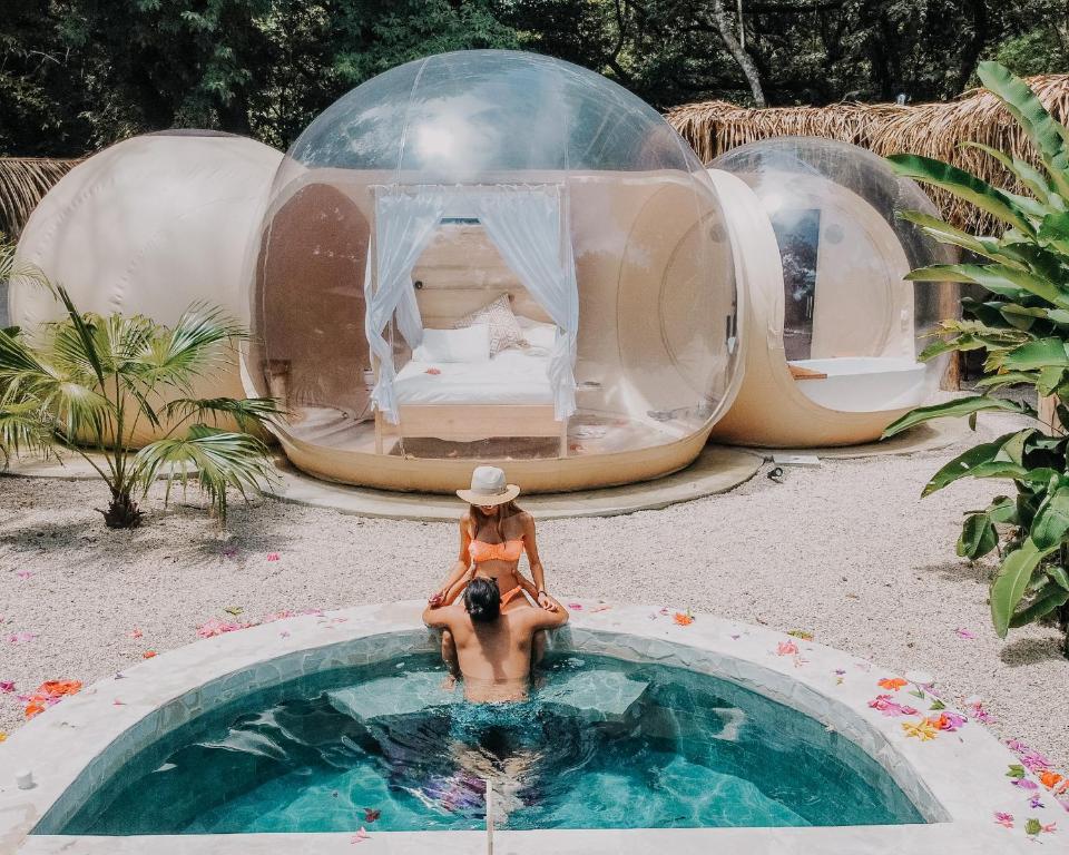 a woman sitting in a swimming pool in a dome house at Nosara Satori Bubbles in Nosara