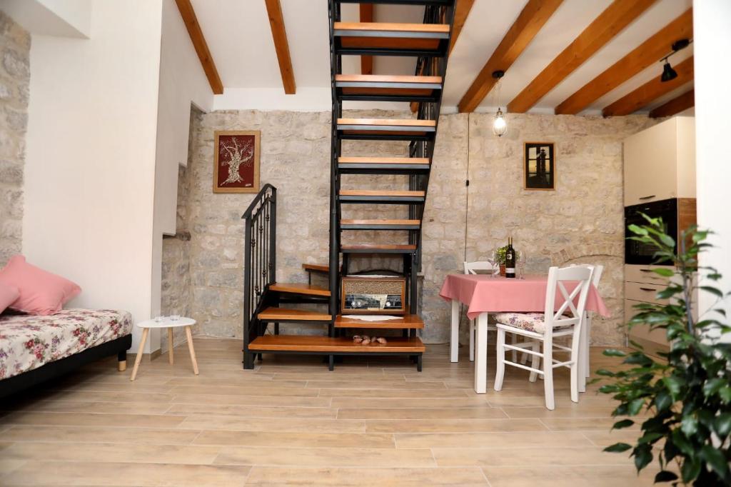 a living room with a spiral staircase and a table at Studio apartman Mihaella in Kaštela