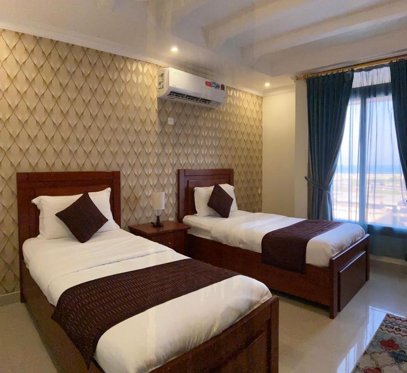 a hotel room with two beds and a window at درة المساكن للآجنحة الفندقية - الواجهة البحرية in Al Khobar