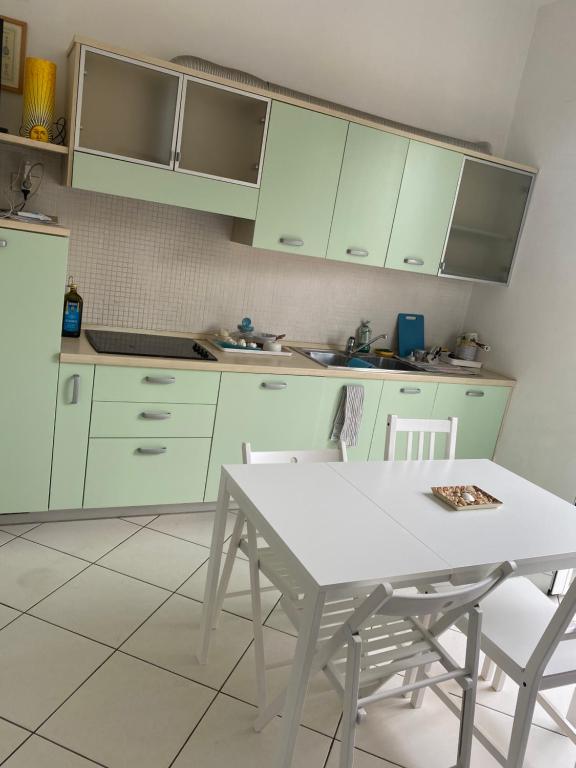a kitchen with green cabinets and a white table and chairs at Apartamento Vittoria Marina di Pietrasanta in Pietrasanta