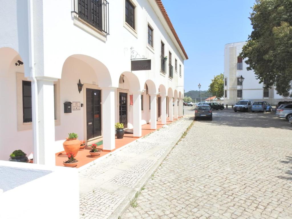 a cobblestone street in front of a white building at Hospedaria Do Senhor da Pedra in Óbidos