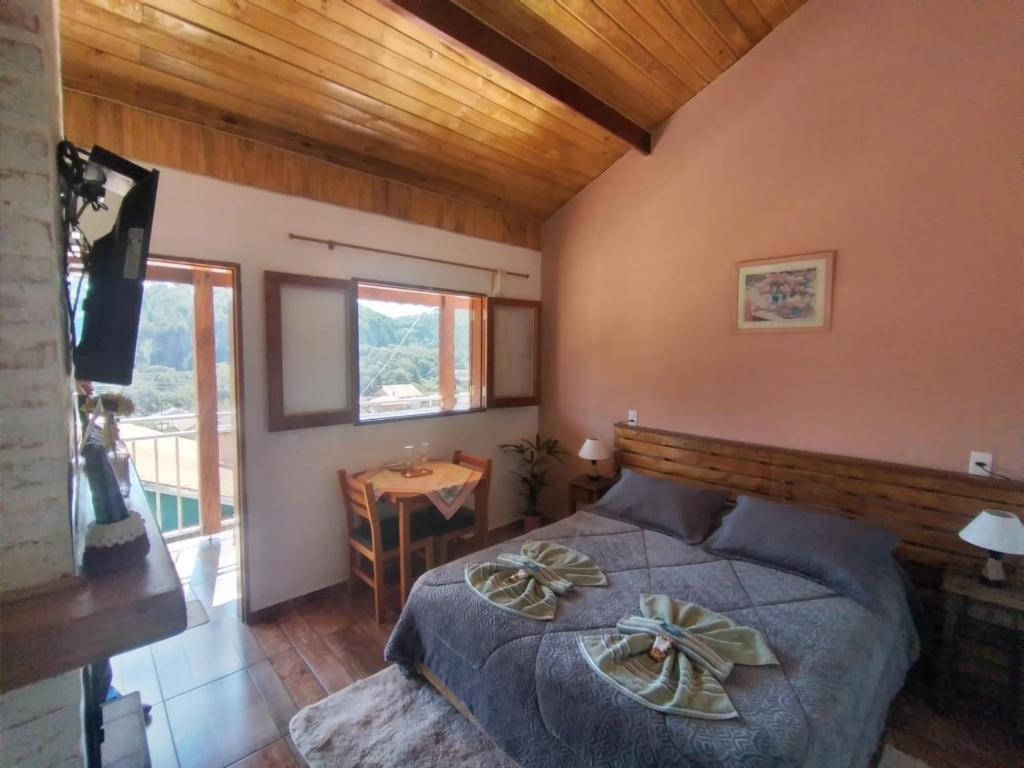 Schlafzimmer mit einem Bett, einem Tisch und einem Fenster in der Unterkunft Recanto lavinia in Monte Verde
