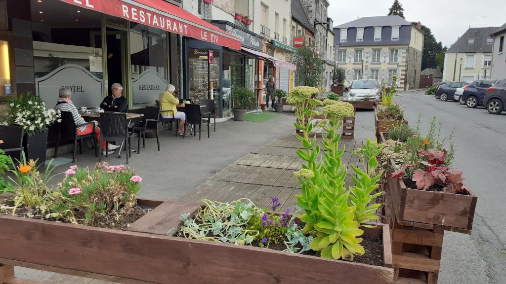 a street with tables and chairs and plants on the sidewalk at Hotel Le XIV in Pontorson