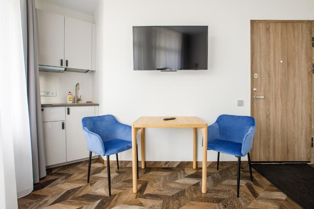 uma cozinha com uma mesa e duas cadeiras azuis em Seaside Central Hotel em Palanga