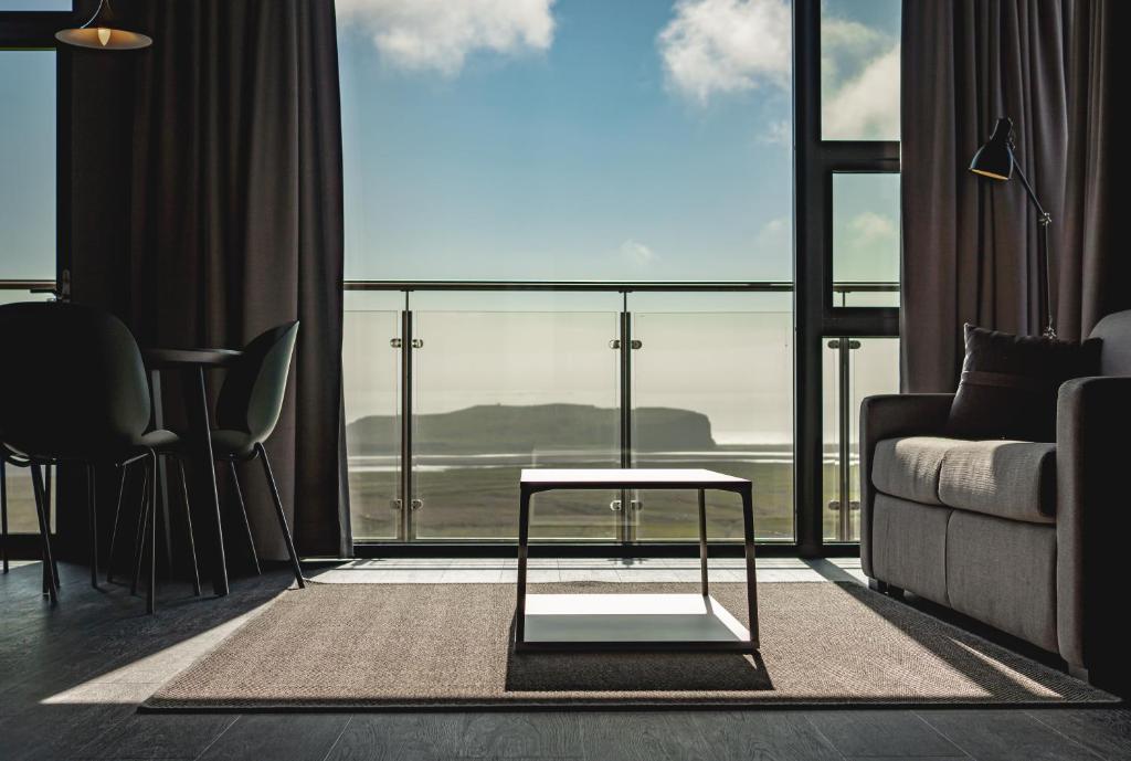 a living room with a couch and a large window at Black Beach Suites in Vík
