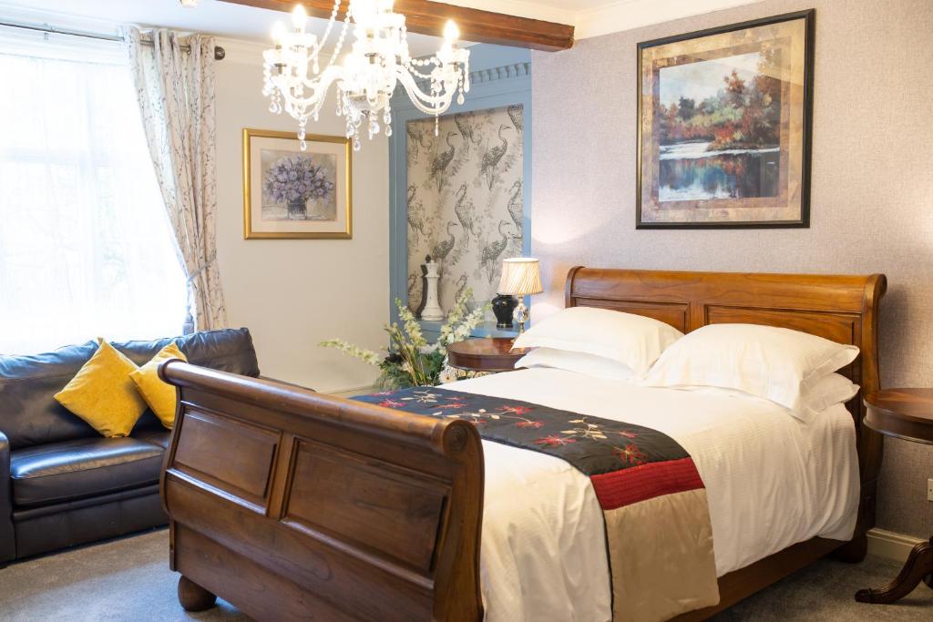 a bedroom with a bed and a couch and a chandelier at The Cheney Arms in Gaddesby