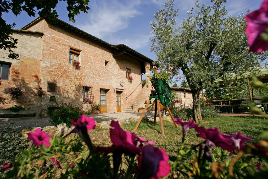 um jardim com flores cor-de-rosa em frente a um edifício em Podere Il Pero em Siena