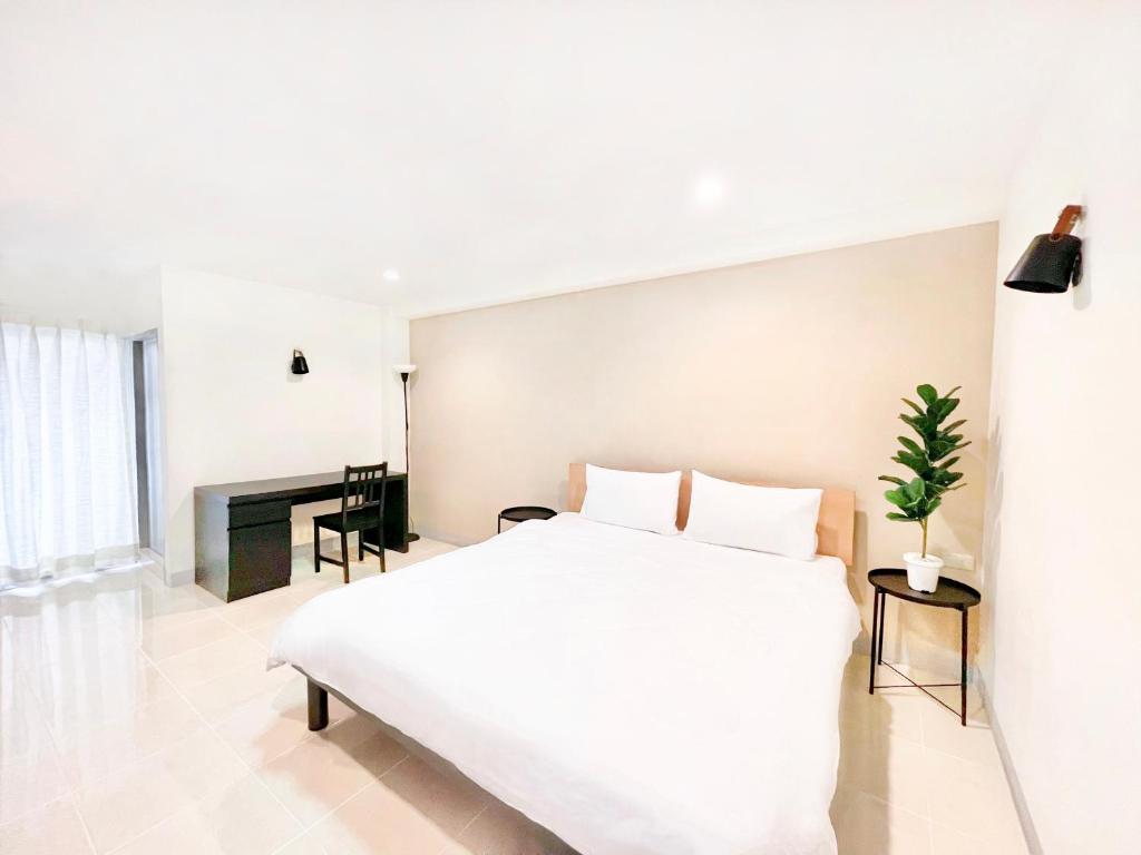 a white bedroom with a white bed and a fireplace at Grand Residence in Bangkok
