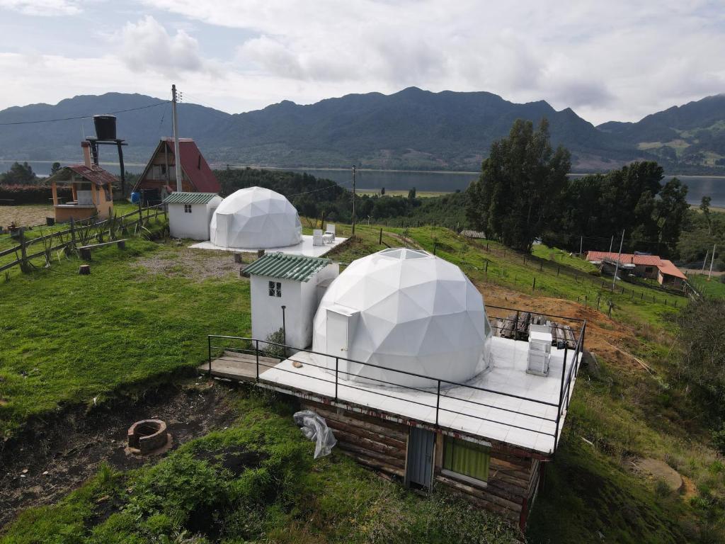 two domes on top of a field with a lake at Glamping Bosques del Neusa in Tausa Viejo