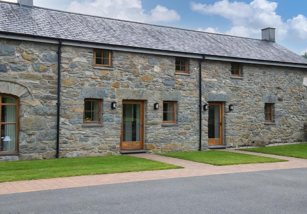 un antiguo edificio de piedra con césped delante en Tyddyn at Hendre Rhys Gethin en Betws-y-coed