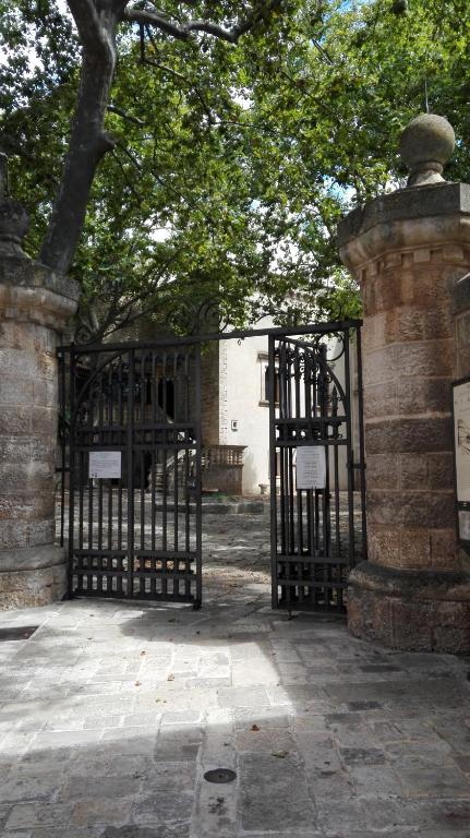 a gate to a building with a tree behind it at B&B CASAVACANZE CHIESA MADRE in Carovigno